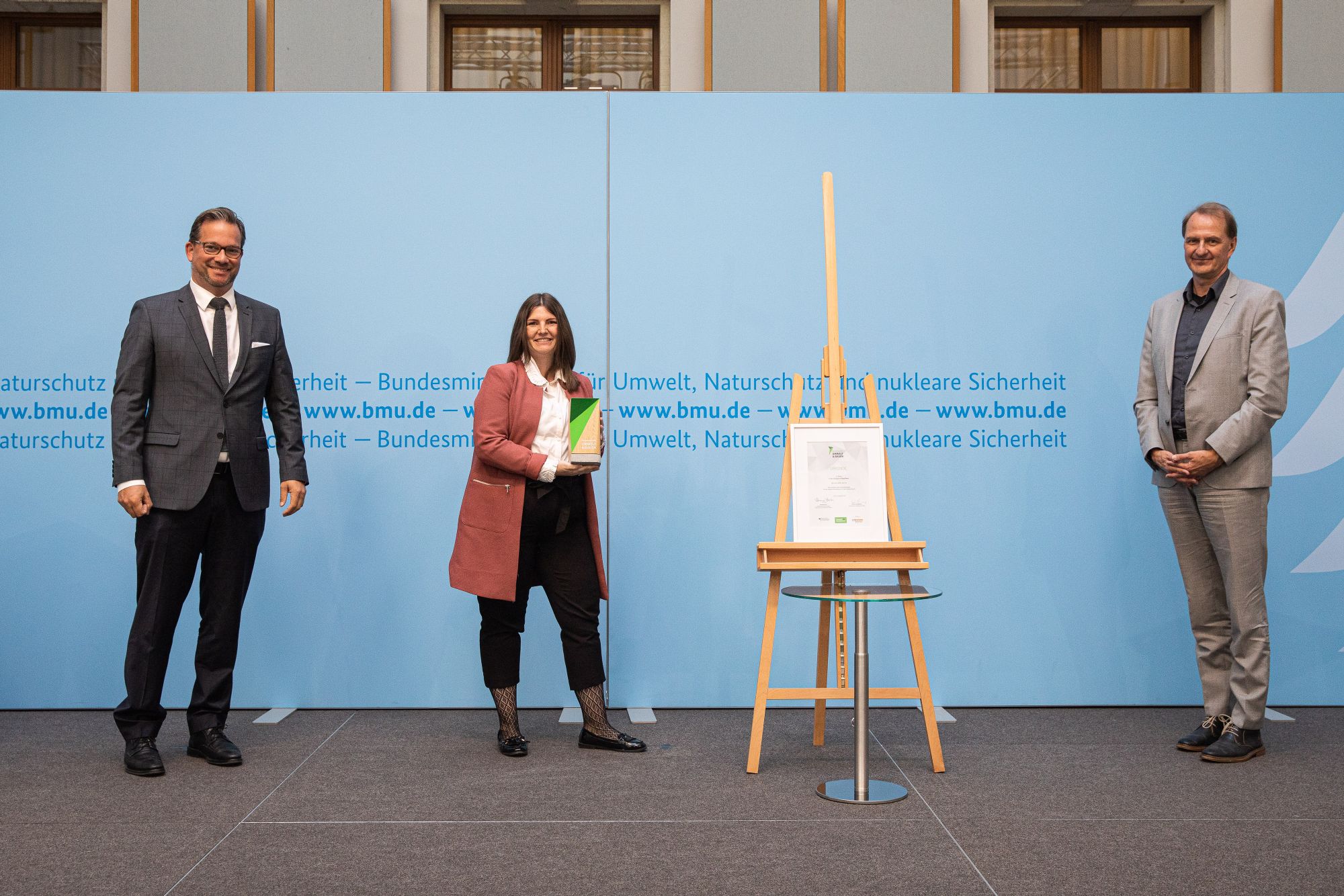 Bei der Preisverleihung (v. l. n. r.): Florian Pronold, Parlamentarischer Staatssekretär – Bundesministerium für Umwelt, Naturschutz und nukleare Sicherheit, Sarah Lüttges, Direktorin Unternehmensentwicklung UTB Projektmanagement GmbH, sowie Prof. Dr. Dirk Messner, Präsident des Umweltbundesamtes. Copyright: BMU-Sascha Hilgers.