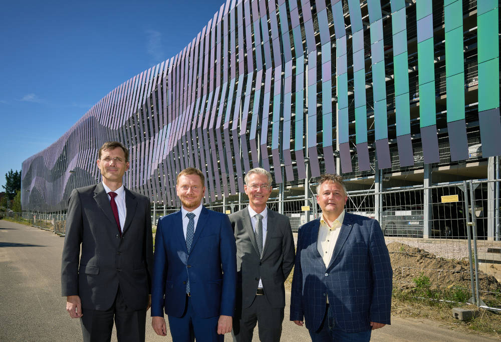 Tobias Meyer,
 Vorstandsvorsitzender DHL Group,
 Michael Kretschmer,
 Patrik Fahrenkamp und Rayk Bergner,
 Oberbürgermeister der Stadt Schkeuditz,
 vor der Fassade des LEJ-Campus-Parkhauses. Quelle: IMMOCOM