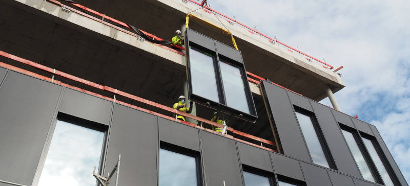 Einbau der platzsparenden Gebäudehülle des OWP12,
die den Energieverbrauch auf ein Minimum reduzieren,
selbst Energie erzeugen und den Schallschutz übernehmen soll. Copyright: Drees & Sommer SE